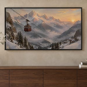 May include: A framed landscape painting depicting a red cable car suspended over a snow-covered mountain valley at sunset. The scene features jagged, snow-capped peaks, evergreen trees, and small cabins nestled in the misty, wintry terrain.