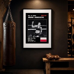 May include: A framed poster featuring a black and white photograph of Joanna Jedrzejczyk, with text reading Hall of Famer, 16-5-0, and her name. It includes stats like height 5'6", weight 115 lbs, reach 65.5", stance orthodox, DOB 18th August 1987, and a Polish flag.