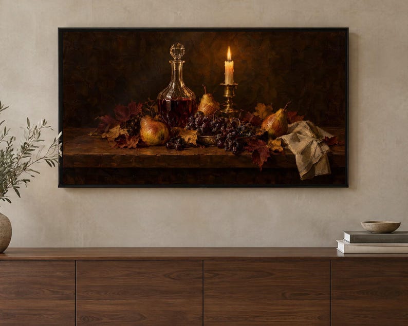 May include: A framed rectangular wall art print depicting a dark still life scene with a glass decanter, a lit candle in a brass holder, pears, and dark grapes resting on a wooden surface amidst scattered autumn leaves and a cloth.