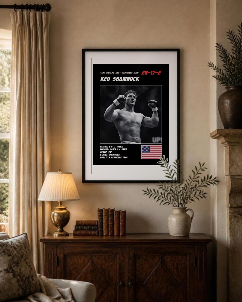May include: A framed poster featuring a black and white photograph of Ken Shamrock with his arms raised. Text includes "The World's Most Dangerous Man", "28-17-2", "Ken Shamrock", and stats: "Height: 6'1", "Weight: 205lbs", "Reach: 73", "Stance: Orthodox", "DOB: 11th February 1964", and a US flag.