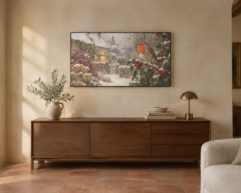 May include: A rectangular wall art print featuring a winter scene with a robin perched on a holly branch in the foreground and a snow-covered cottage in the background. The artwork is framed in a thin black border and displayed on a wall.