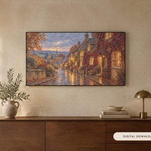 K&ouml;nnte beinhalten: Ein rechteckiger Wandkunstdruck, der eine gepflasterte Dorfstra&szlig;e in der Abendd&auml;mmerung zeigt, mit herbstlich bewachsenen Steinh&auml;usern, leuchtenden Fenstern und einem Kirchturm in der Ferne unter einem weichen Himmel, mit dem Text Digital Download.