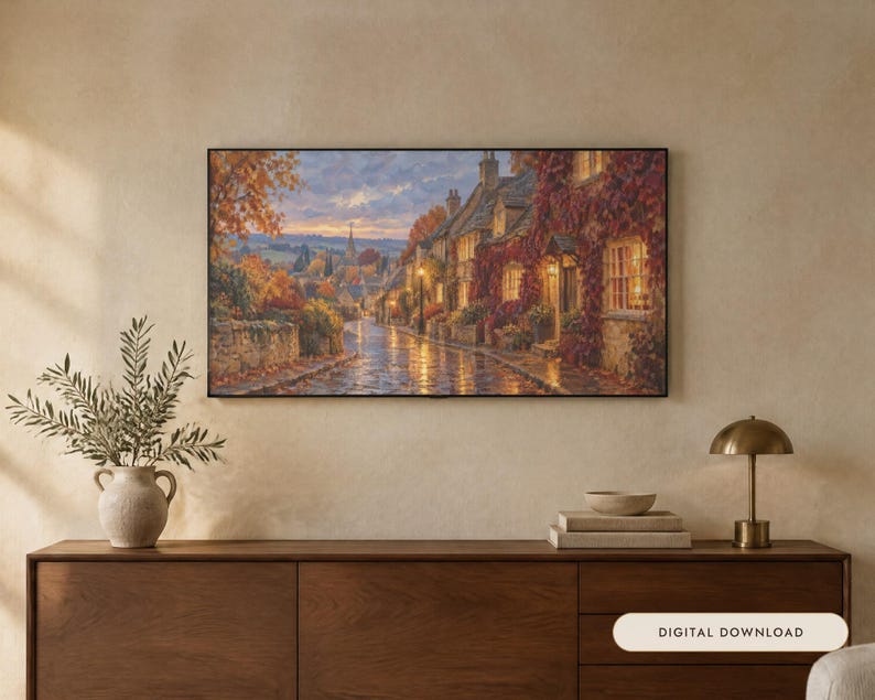 K&ouml;nnte beinhalten: Ein rechteckiger Wandkunstdruck, der eine gepflasterte Dorfstra&szlig;e in der Abendd&auml;mmerung zeigt, mit herbstlich bewachsenen Steinh&auml;usern, leuchtenden Fenstern und einem Kirchturm in der Ferne unter einem weichen Himmel, mit dem Text Digital Download.
