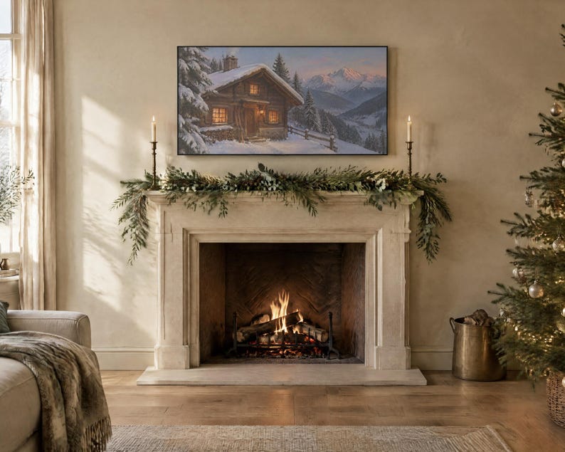 May include: A rectangular television screen mounted above a stone fireplace displays a winter landscape painting of a wooden cabin in the snow. The fireplace mantel is decorated with green pine garland and two tall, thin metal candle holders.