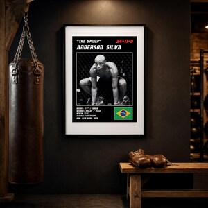 May include: A framed black and white poster of Anderson Silva, nicknamed The Spider, featuring his fight record 34-11-0, physical stats, and the Brazilian flag. The poster displays his height, weight, reach, stance, and date of birth.