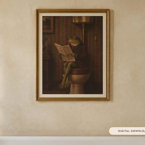May include: A framed wall art print featuring an anthropomorphic green frog wearing a dark jacket, sitting on a toilet while reading a newspaper. The scene is set in a room with striped wallpaper and a vintage-style toilet fixture.