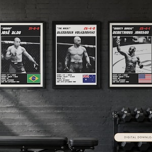 May include: Three framed black and white posters featuring UFC fighters Jos&eacute; Aldo, Alexander Volkanovski, and Demetrious Johnson. Each poster displays the fighter's nickname, record, height, weight, reach, stance, birth date, and national flag.