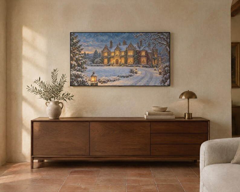 May include: A rectangular wall art print depicting a large stone manor house covered in snow at twilight. The scene features a winding driveway, glowing outdoor lanterns, and snow-dusted trees under a soft, cloudy sky with warm interior lighting.