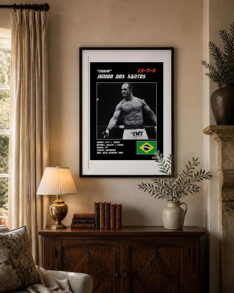 Peut inclure: Une affiche encadr&eacute;e avec une photo en noir et blanc de Junior Dos Santos, le texte "Cigano" 23-11-0, taille 193cm, poids 120kg, allonge 77", posture orthodoxe, date de naissance 30 janvier 1984 et le drapeau du Br&eacute;sil.