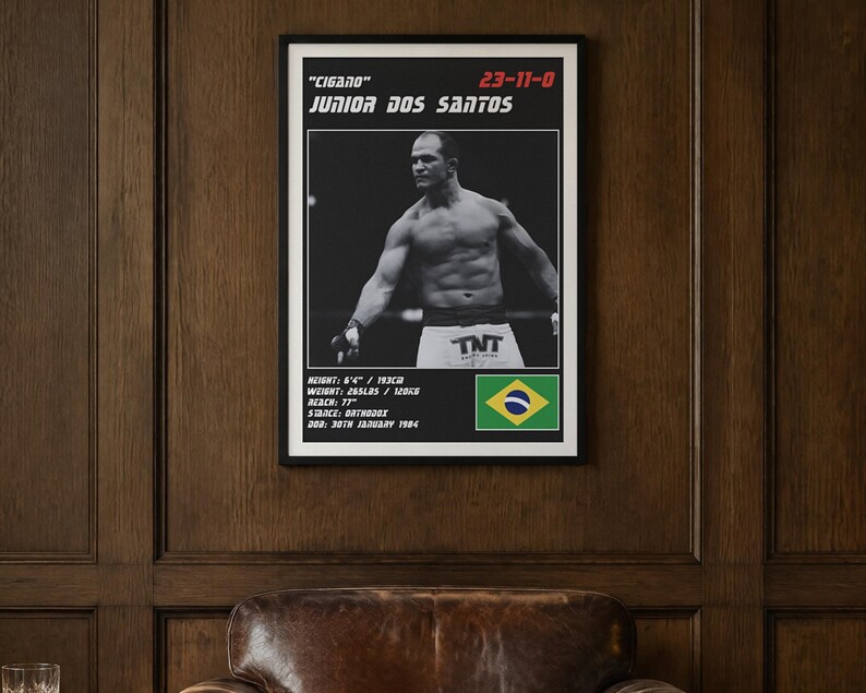 Peut inclure: Une affiche encadr&eacute;e pr&eacute;sentant une photographie en noir et blanc de Junior Dos Santos, surnomm&eacute; Cigano, avec un palmar&egrave;s de 23-11-0. L'impression inclut ses statistiques physiques, le drapeau br&eacute;silien et le texte TNT sur son short.