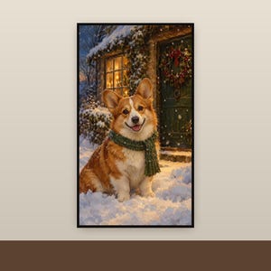 Op de afbeelding: Een ingelijste kunstdruk met een bruin-witte Corgi die een donkergroene gebreide sjaal draagt, zittend in de sneeuw voor een huis met een verlicht raam en een feestelijke krans aan de deur tijdens een winteravond.