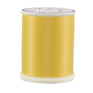 May include: A spool of yellow thread with a white label that reads "COATS & CLARK'S - 100% COTTON - 50 WT - 250 YARDS".
