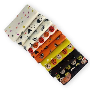 May include: A collection of ten folded fabric squares featuring various Halloween-themed patterns including orange pumpkins, black spiders, white ghosts, witch hats, and colourful stars on white, orange, lime green, and black backgrounds.