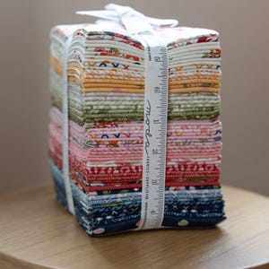 Peut inclure: Un ensemble de carrés de tissu aux couleurs et motifs floraux variés, liés par un ruban blanc imprimé "moda fabrics". La pile de tissu mesure environ 13 cm de haut, parfait pour le quilting et les projets créatifs.