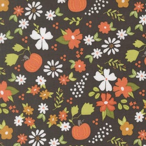 Op de afbeelding: Een donkerbruine stof met een herhalend patroon van oranje pompoenen, witte en oranje bloemen en lichtgroene bladeren. Het ontwerp bevat kleine groepjes witte stippen en steeltjes, wat zorgt voor een dicht, gebalanceerd bloemmotief.