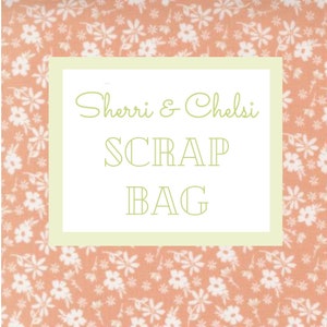 May include: A peach-colored fabric with a white floral pattern. The fabric has a white border with the text "Sherri & Chelsi SCRAP BAG" in green.