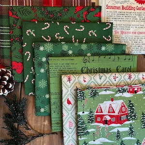 May include: A collection of Christmas-themed fabric pieces in various patterns. Designs include candy canes, snowflakes, red houses, and Christmas trees on green backgrounds. Some fabrics feature text, including "Christmas Carol."