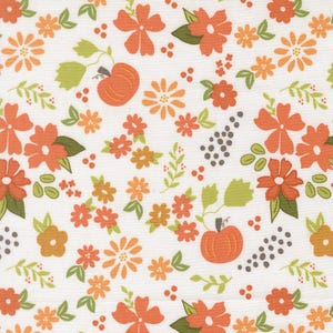 May include: A white fabric featuring a repeating pattern of orange pumpkins, various orange and yellow flowers, green leaves, and small clusters of dark gray dots. The design is evenly spaced across the surface, showcasing a seasonal botanical motif.