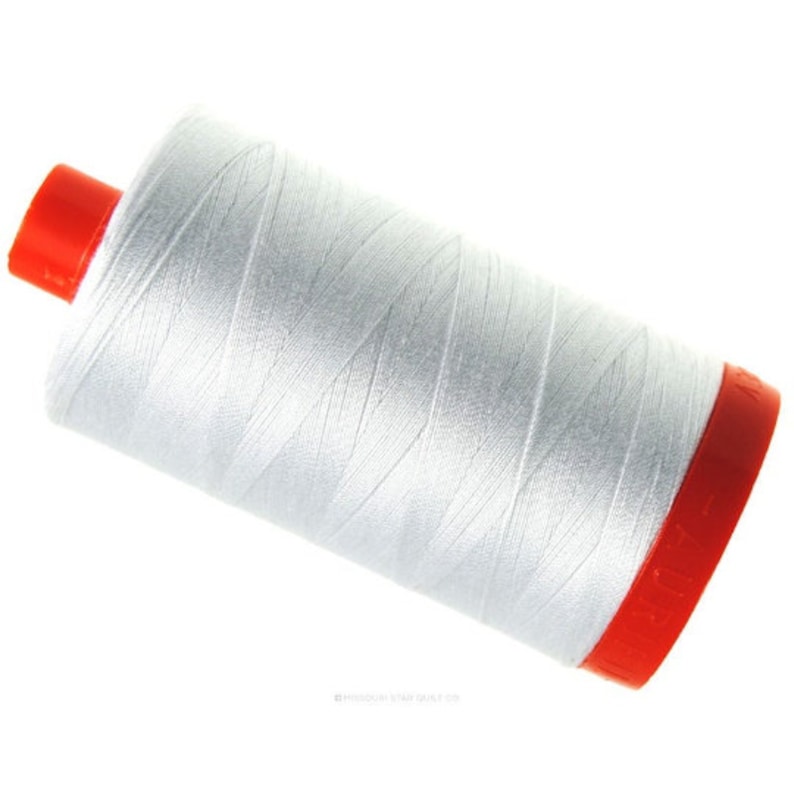 May include: A white thread spool with a red cap. The thread is tightly wound and has a smooth appearance. The spool is angled, highlighting the thread's texture and colour. Suitable for sewing and quilting.