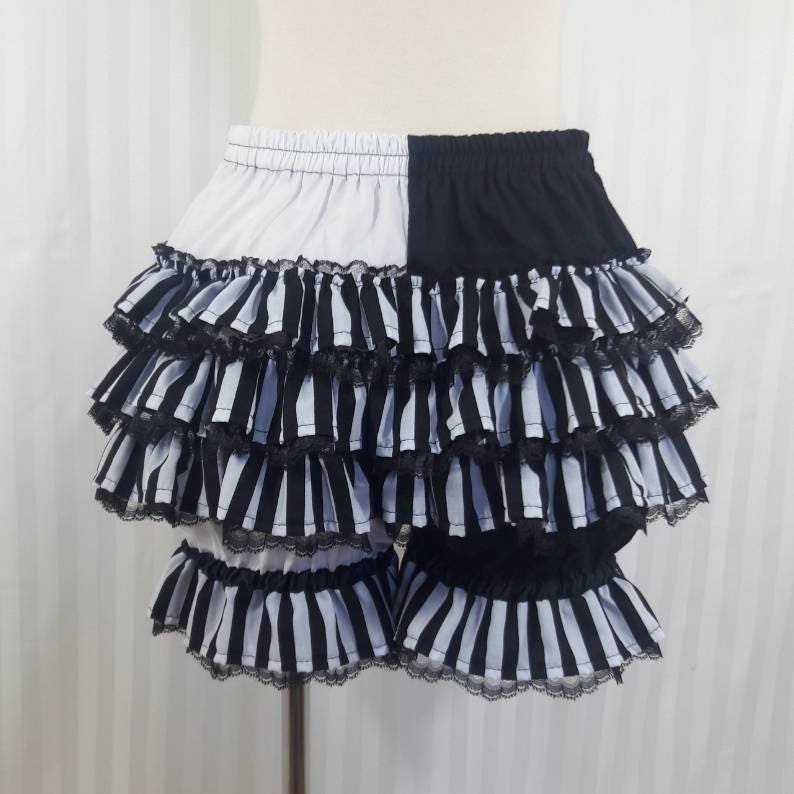 Pode incluir: Shorts de babados listrados em preto e branco com acabamento em renda preto e branco. Os shorts s&atilde;o divididos ao meio, com um lado branco e o outro preto.