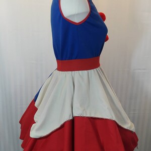 Puede incluir: Un vestido azul y rojo con una falda blanca. El vestido tiene un ribete rojo alrededor del escote y una cintura roja. La falda tiene una capa blanca y una capa roja.