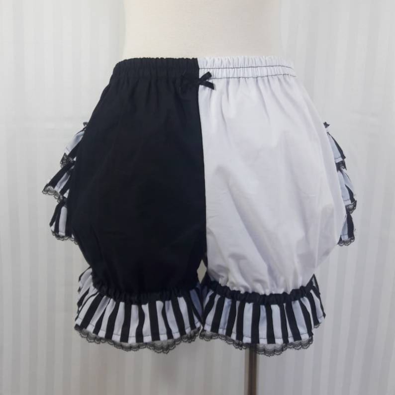 Pode incluir: Bloomers de algod&atilde;o com acabamento de babados em listras pretas e brancas com um design de bloco de cores preto e branco.