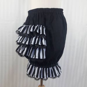 Pode incluir: Bloomers de algod&atilde;o preto com uma bainha de babados de listras brancas e pretas. O babado &eacute; em camadas e tem uma bainha de renda preta.