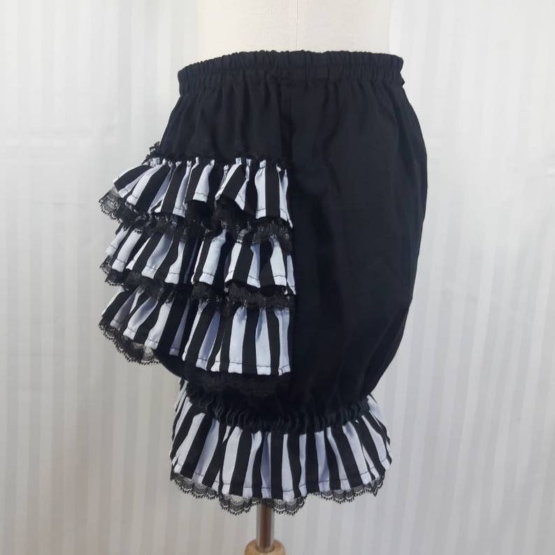 Pode incluir: Bloomers de algod&atilde;o preto com uma bainha de babados de listras brancas e pretas. O babado &eacute; em camadas e tem uma bainha de renda preta.