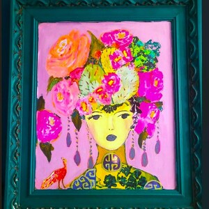 May include: A vibrant painting of a woman with a floral headdress and a peacock. The artwork features a pink background, a teal frame, and a yellow face. The woman's attire includes a yellow collar with a decorative emblem and a patterned green and blue top. The painting is colorful and eye-catching.