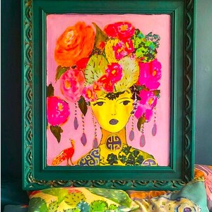 May include: A framed painting of a woman with a yellow face and a floral headdress. The artwork features a pink background and a green frame. The woman's neck is adorned with a decorative pattern, and a small bird is visible on the left.
