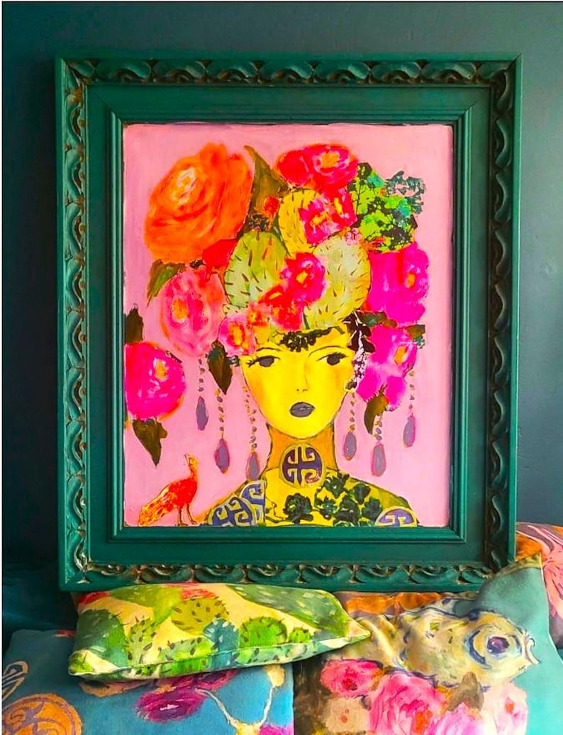 May include: A framed painting of a woman with a yellow face and a floral headdress. The artwork features a pink background and a green frame. The woman's neck is adorned with a decorative pattern, and a small bird is visible on the left.