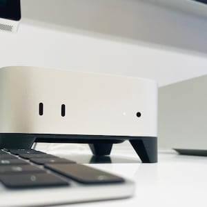 Könnte beinhalten: Ein silberner und schwarzer Computer mit rechteckiger Form und abgerundeten Kanten. Der Computer hat drei kleine schwarze Kreise auf der Vorderseite.