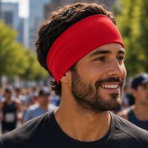 May include: A solid bright red fabric headband worn around the head. The headband is made of a smooth, stretchy material that sits flat against the hair, covering the forehead and ears, providing a simple and functional accessory for active use.