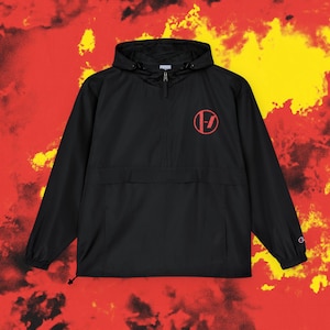 May include: Black anorak jacket with a hood and a red circular logo on the chest. The jacket features a half-zip, a front pocket, and a drawstring hem. The background is a mix of red and yellow.