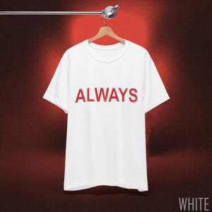 May include: A white t-shirt with the word "ALWAYS" printed in red across the chest. The shirt is hanging on a wooden hanger against a red background. The word "WHITE" is visible in the bottom right corner.
