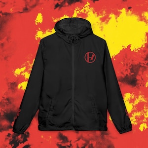 May include: Black hooded jacket featuring a red logo on the chest and sleeve. The jacket has a full zip and a drawstring hood. The background is a mix of red and yellow colours.