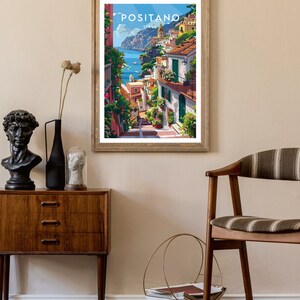 May include: A framed poster with a colorful illustration of Positano, Italy. The poster features a view of the town's colorful buildings, winding streets, and the Mediterranean Sea.