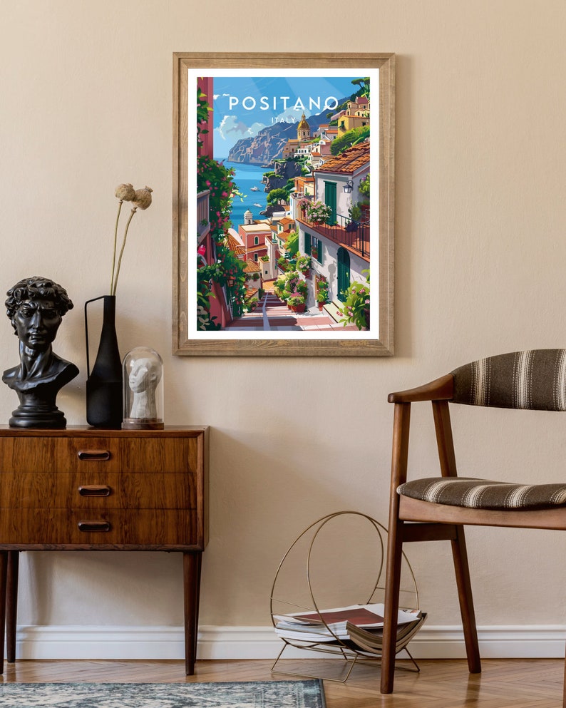 May include: A framed poster with a colorful illustration of Positano, Italy. The poster features a view of the town's colorful buildings, winding streets, and the Mediterranean Sea.