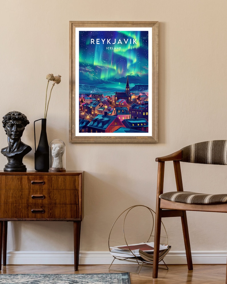 Pode incluir: Um p&ocirc;ster de viagem vintage com uma vista da cidade de Reykjavik, Isl&acirc;ndia, com a aurora boreal no c&eacute;u. O p&ocirc;ster tem uma moldura de madeira e o texto "REYKJAVIK ICELAND" no topo.