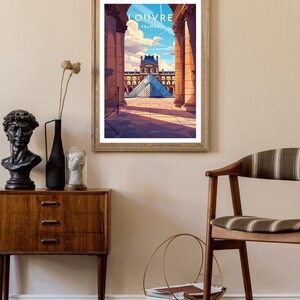 May include: A framed print of the Louvre Museum in Paris, France. The print features a view of the museum's iconic glass pyramid, seen through a colonnade of columns. The text "LOUVRE FRANCE" is printed at the top of the print.