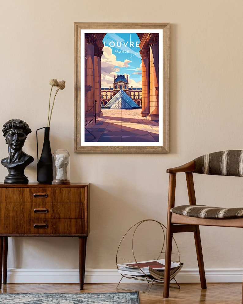 May include: A framed print of the Louvre Museum in Paris, France. The print features a view of the museum's iconic glass pyramid, seen through a colonnade of columns. The text "LOUVRE FRANCE" is printed at the top of the print.