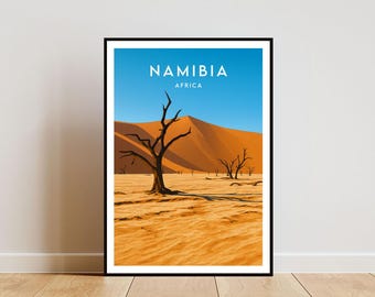 May include: Framed art print featuring a desert landscape in Namibia, Africa. The artwork displays a vibrant blue sky, orange sand dunes, and silhouetted trees. The word "NAMIBIA" is printed at the top.