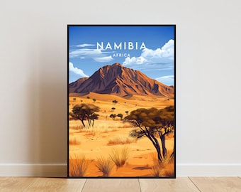 Op de afbeelding: Een ingelijste poster met een kleurrijke illustratie van een bergketen in een woestijnlandschap. De poster heeft de tekst "NAMIBIA AFRIKA" bovenaan.