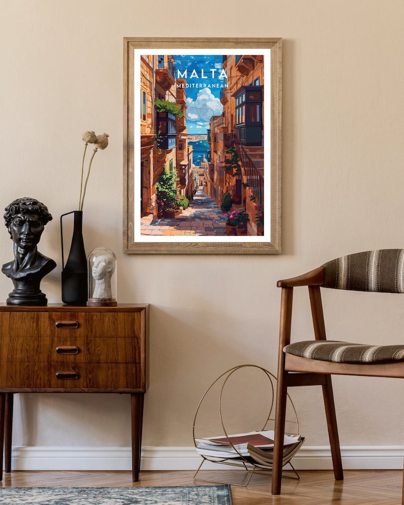 May include: A vintage travel poster featuring a narrow, cobblestone street in Malta. The street is lined with colorful buildings and has a view of the Mediterranean Sea in the distance. The poster has the text "MALTA MEDITERRANEAN" at the top.