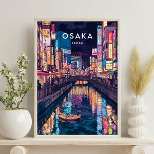 May include: A vibrant illustration of Osaka, Japan at night. The image features a canal with colorful reflections of the city's lights. A small boat with two people is visible in the canal. The text "OSAKA JAPAN" is displayed at the top of the image.