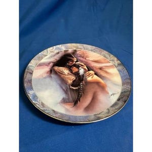 May include: A decorative ceramic plate with a colorful design featuring a couple embracing. The plate has a gold rim and a swirling pattern of blue, purple, and white.