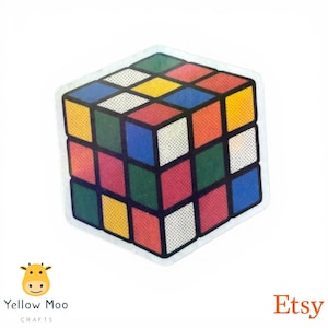 Pu&ograve; includere: Un adesivo con un design del Cubo di Rubik con bordo bianco. Il cubo presenta quadrati rossi, blu, gialli, verdi e arancioni. L'adesivo ha uno stile retr&ograve;. Il logo Etsy si trova nell'angolo in basso a destra.
