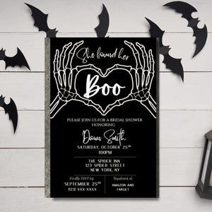 May include: Black and white Halloween-themed bridal shower invitation. The invitation features skeleton hands forming a heart around the word "Boo." Includes event details: date, time, location, and RSVP information. Decorative black bat cutouts are scattered around the invitation.