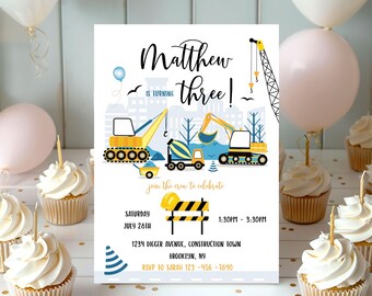 Puede incluir: Invitación a una fiesta de cumpleaños con temática de construcción con una excavadora amarilla, una mezcladora de cemento azul y una grúa amarilla. La invitación dice "¡Matthew cumple tres!" e incluye la fecha, la hora y el lugar de la fiesta.