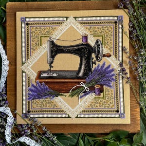 May include: A square cross-stitch embroidery on tan fabric featuring a black vintage sewing machine centered within a white lace diamond border. The design includes purple lavender sprigs, a small purple thread spool, and decorative gold beadwork.